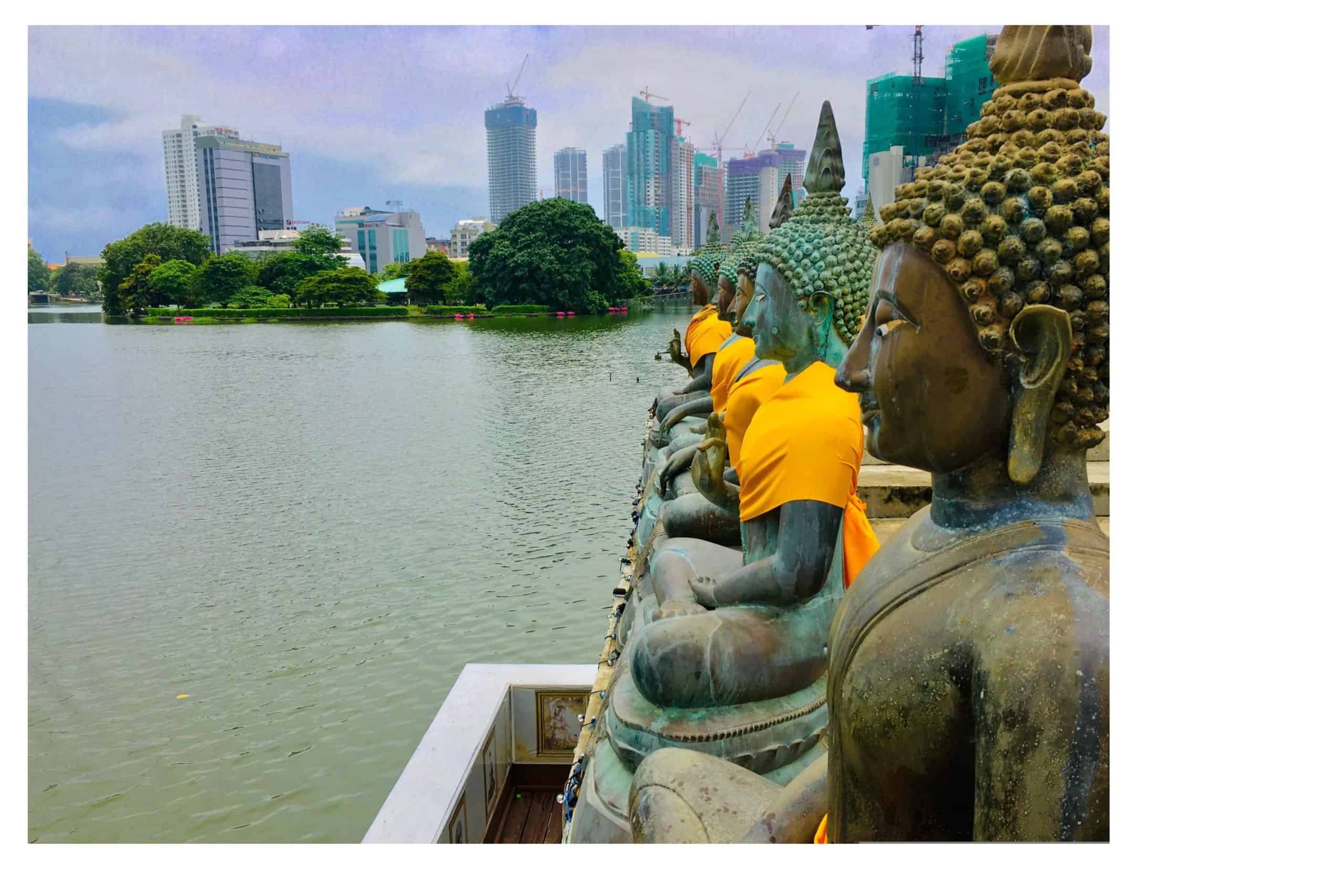 Religious statues facing out towards the Beira lake in Colombo. With high rise buildings in the background
