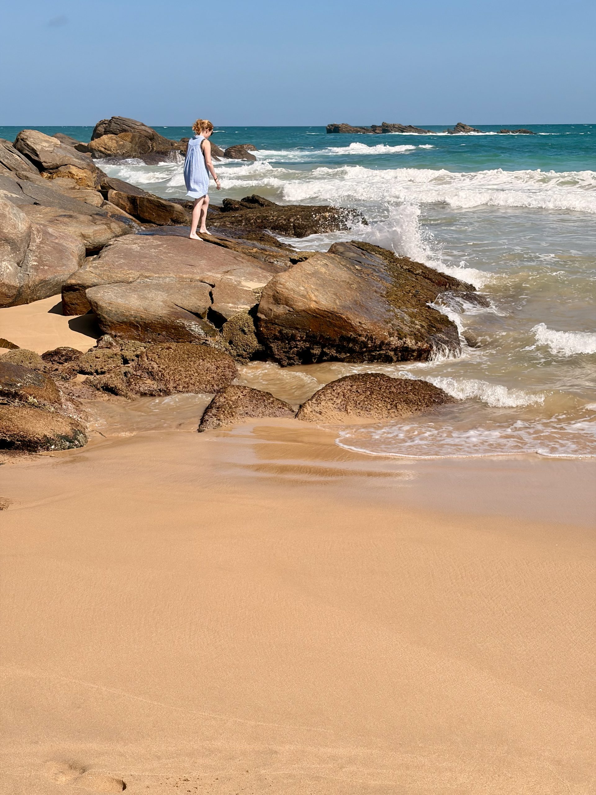 Young lady walking on rocks on quiet beach in Tangalle, Sri lanka